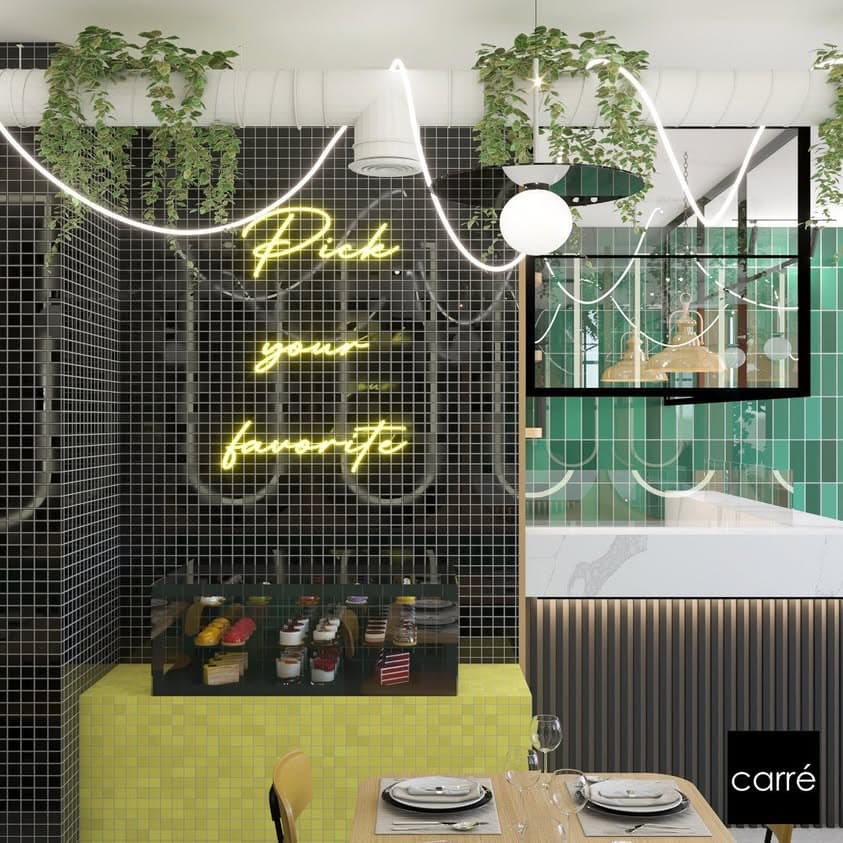 Mur me mozaik të zi, neon i verdhë dhe vitrinë ëmbëlsirash
